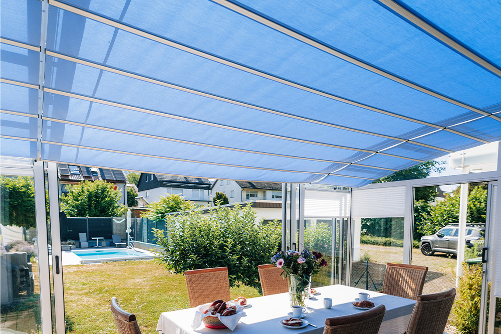 Interior view of the TOPAS Solar Veranda patio cover with blue roof shading and a view of the garden.