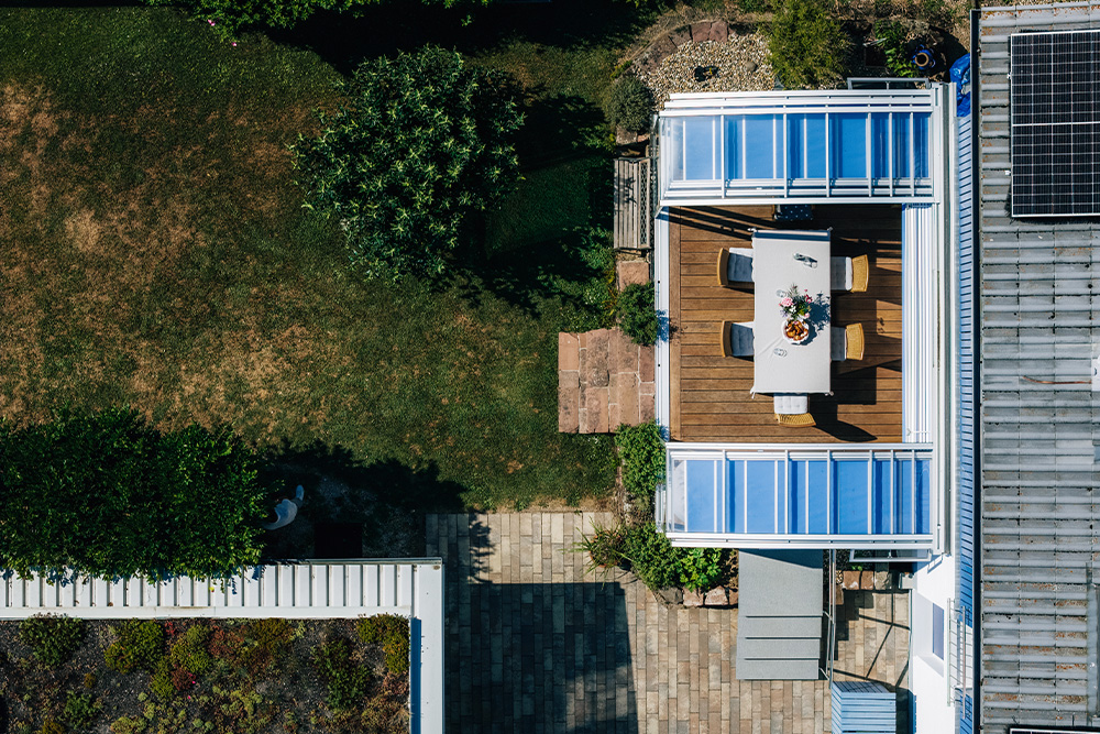 A bird's-eye view of the patio with the dining table, the VÖROKA canopy, and the adjacent garden.